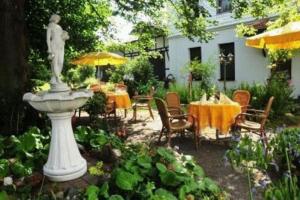 un jardín con una estatua, mesas y sillas en Hotel Luginsland, en Schleiz