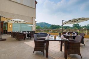 a restaurant with tables and chairs and a balcony at The Fern An Ecotel Hotel, Lonavala in Lonavala