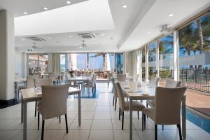 a restaurant with tables and chairs and large windows at Mantra Mackay in Mackay