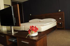 a bedroom with a bed with a television and a vase of flowers at Glass House Kosice in Košice