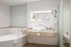 a white bathroom with a tub and a sink at Landhotel Böld Oberammergau in Oberammergau