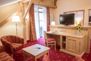 a room with a desk with a television and chairs at Landhotel Böld Oberammergau in Oberammergau