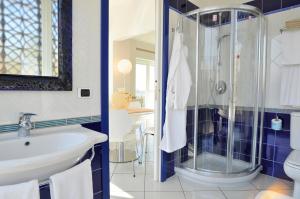 a bathroom with a shower and a sink and a toilet at Villa Grachira in Fertilia +44 photos