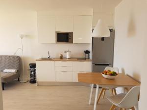 a kitchen with white cabinets and a table with a bowl of fruit at Isora Coast in Puerto de Santiago