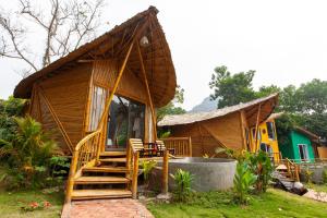 a small wooden house with a porch and stairs to it at Trang An Lamia Bungalow in Ninh Binh