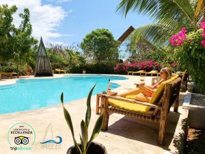 a woman sitting on a chair next to a swimming pool at Breeze Residence Apartments in Kiwengwa