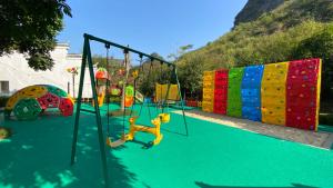 a playground with colorful swings and slides on a green surface at Banyan Tree Yangshuo in Yangshuo