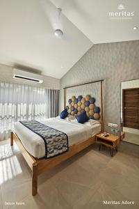 a bedroom with a large bed with blue pillows at Meritas Adore Resort in Lonavala