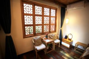 Habitación con mesa, sillas y ventana en Begonia Flowers Guesthouse en Suzhou