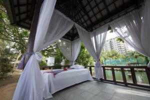 1 dormitorio con 1 cama con cortinas blancas en Ancasa Residences, Port Dickson by Ancasa Hotels & Resorts en Port Dickson