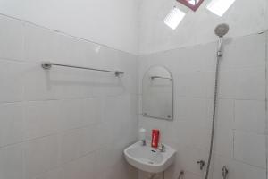 ein weißes Badezimmer mit einem Waschbecken und einem Spiegel in der Unterkunft RedDoorz Syariah near Terminal Batu Ampar 2 in Balikpapan