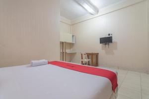 1 dormitorio con 1 cama blanca y TV en RedDoorz Syariah near Terminal Batu Ampar 2 en Balikpapan