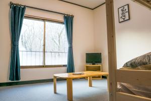Schlafzimmer mit einem Bett, einem Tisch und einem Fenster in der Unterkunft Myoko House in Myōkō