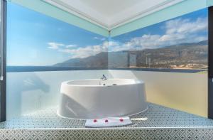 a bathroom with a white tub in front of a window at Mandalina Suites in Kaş
