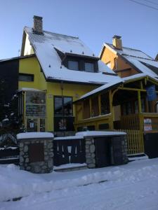 une maison jaune recouverte de neige dans l'établissement Penzión Skitour, à Stará Lesná