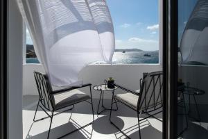 a balcony with two chairs and a table and a view of the water at Nimbus Mykonos in Agios Stefanos