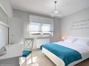 a white bedroom with a bed and a window at Apartament BLUE BAY Darłówko in Darlowko