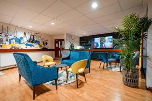 une salle d'attente avec des chaises bleues et une télévision dans l'établissement Inverness Youth Hostel, à Inverness