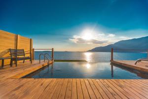 a swimming pool on a wooden deck with the sun setting at Mandalina Suites in Kaş