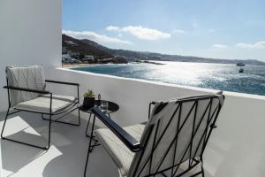 a balcony with two chairs and a table and water at Nimbus Mykonos in Agios Stefanos