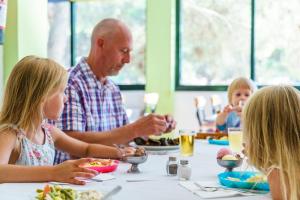 a man and two children sitting at a table eating food at Playa Parc Apartments in Son Parc