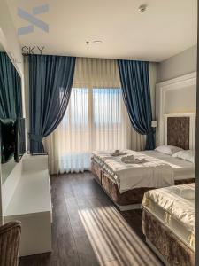 2 Betten in einem Hotelzimmer mit blauen Vorhängen in der Unterkunft Sky Hotel in Prizren