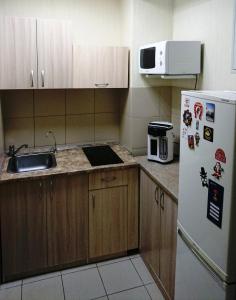 cocina con armarios de madera y nevera blanca en Hostel On-day, en Novosibirsk