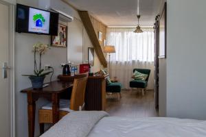 a bedroom with a bed and a desk with a tv on the wall at B&B Aan het Park Eindhoven in Eindhoven