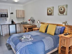 1 Schlafzimmer mit einem blauen und weißen Bett und einer Küche in der Unterkunft Mountain Breeze Log Cabins in Stormsrivier