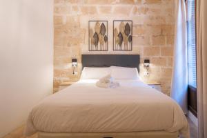 een slaapkamer met een wit bed met twee foto's aan de muur bij Vintage Palma Palace Apartments TI in Palma de Mallorca