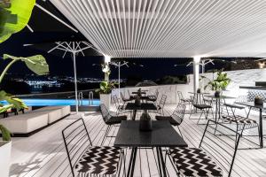 a patio with tables and chairs and a pool at Nimbus Mykonos in Agios Stefanos
