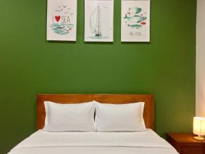 a green bedroom with a bed and three pictures on the wall at Eden House & Coffee Con Dao in Con Dao