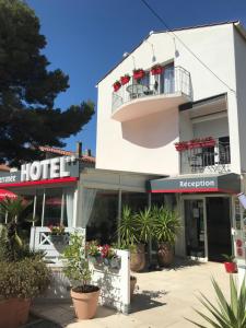 un hotel blanco con balcón y macetas en Hôtel Le Méditerranée, en Hyères