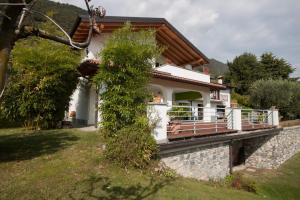 a white house with a porch and a stone wall at Villa 3 Olivi - sleep 5 - in Lenno in Lenno
