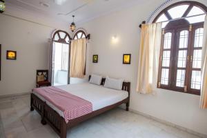 a bedroom with a bed in a room with windows at Jashoda Mystic Haveli in Pushkar
