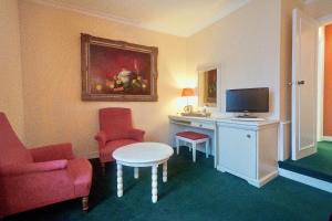 a hotel room with a desk with a tv and chairs at ARTEMIS SUITE in Barbizon