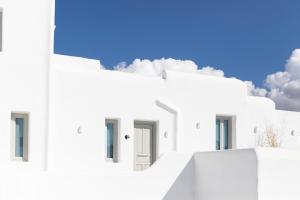 a row of white buildings with a blue sky in the background at Nimbus Mykonos in Agios Stefanos