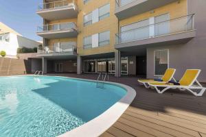 a swimming pool with two chairs and a building at Baia Residence 3 - Holiday Apartments - By SCH in São Martinho do Porto