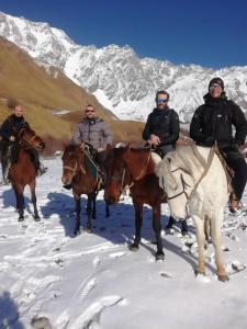 a group of men riding horses in the snow at Ushguli Hotel Riho in Ushguli +53 photos