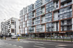 an apartment building on a city street with a car at Apartments Konstruktorska by Renters Prestige in Warsaw