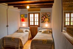 two beds in a room with two windows at Casas Rurales Pradina I y II in Luanco