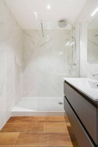 een witte badkamer met een douche en een wastafel bij 2 chambres Terrasse Parking Toulouse Centre Gare in Toulouse