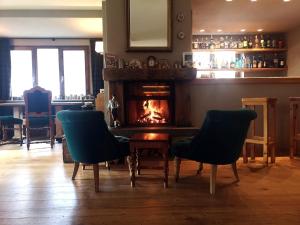a bar with a fireplace and two chairs and a table at Alpi & Golf Hotel in Bormio