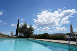 a swimming pool with a blue sky and clouds at Wine Resort Dievole in Vagliagli