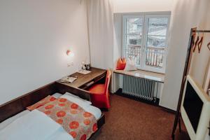 a hotel room with a bed and a desk and a window at Gasthof Eberhard - Hof, Wirtshaus & Herberge in Sankt Michael in Obersteiermark