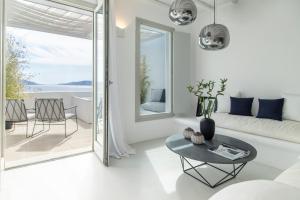 a white living room with a table and a couch at Nimbus Mykonos in Agios Stefanos