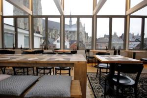a large room with tables and chairs and windows at 3 Paardekens - City Centre Hotel in Mechelen