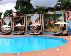 a pool with chairs and umbrellas in front of a hotel at Novotel Port Harcourt in Port Harcourt