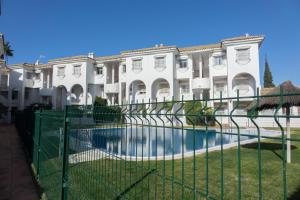 une clôture en face d'un bâtiment avec piscine dans l'établissement Apartamento Alextia La Barrosa, à Chiclana de la Frontera