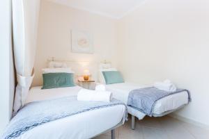 two twin beds in a room with white walls at IM on Centro Historico in Lagos